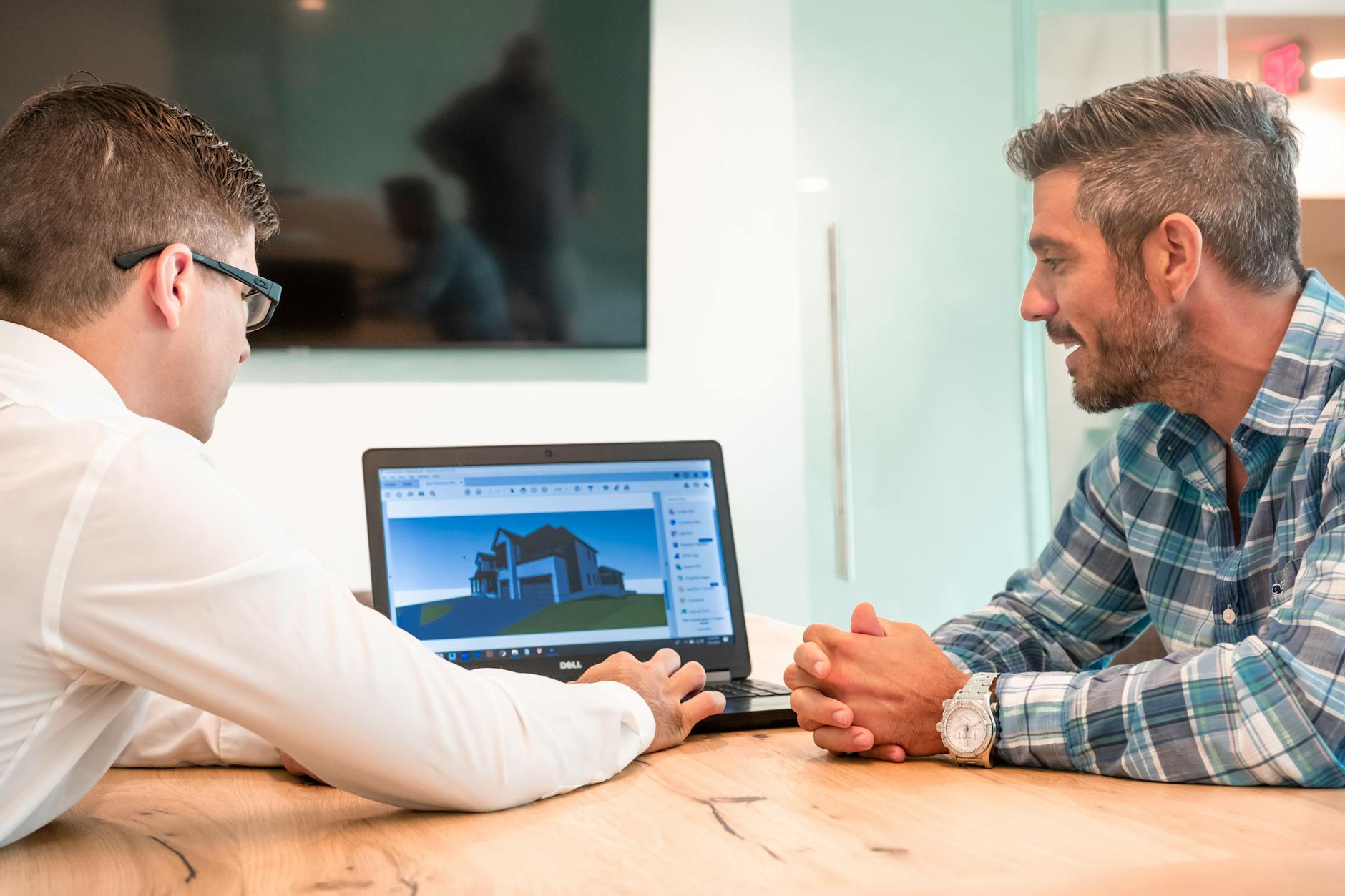 Profissionais imobiliários em reunião analisando dados em notebook e documentos em ambiente corporativo