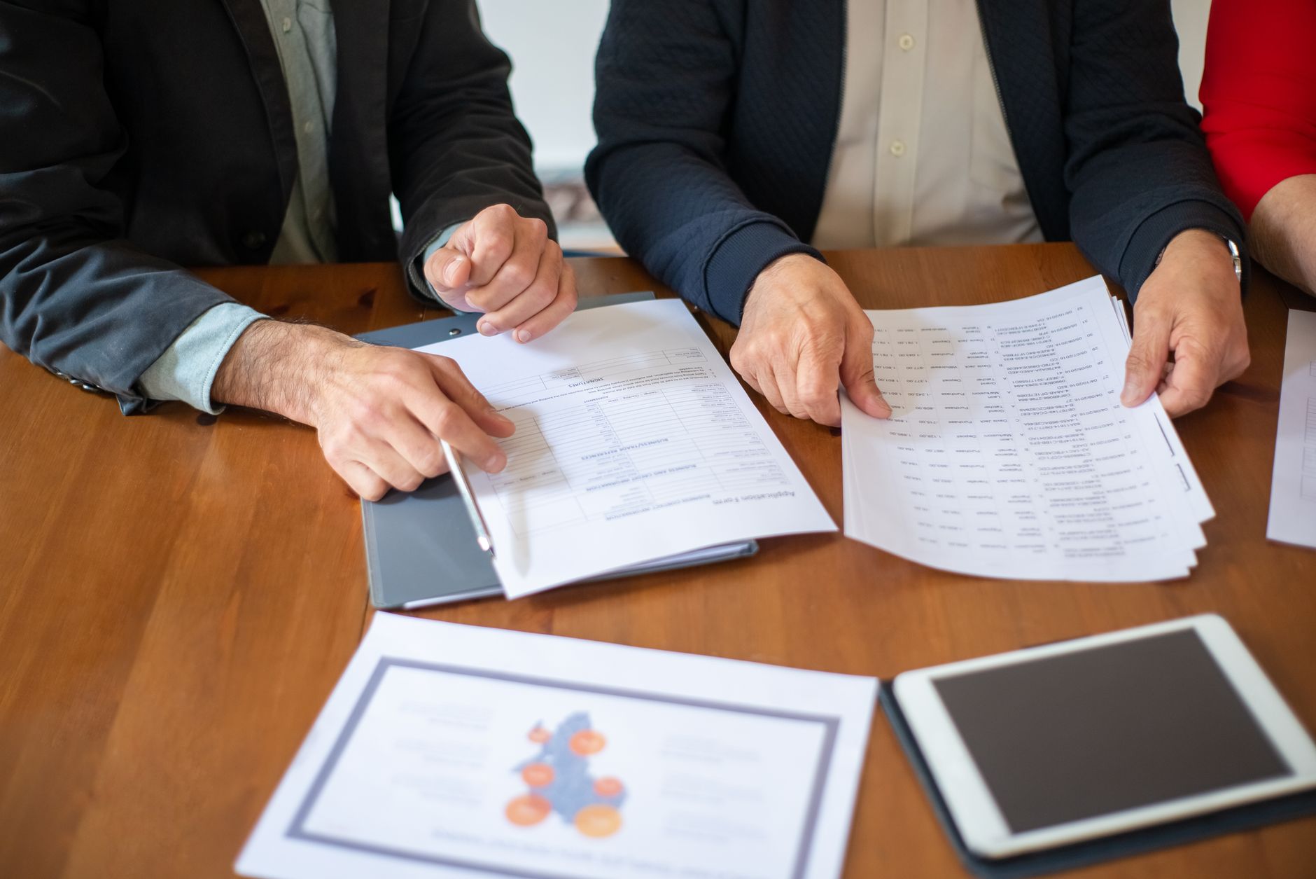 Reunião profissional com documentos e contratos imobiliários sendo analisados em ambiente corporativo
