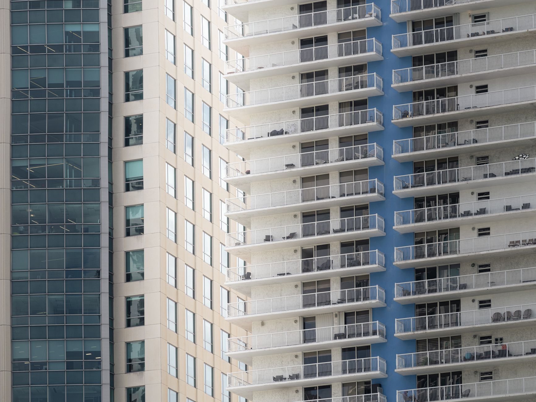 Profissional imobiliário apresenta proposta para cliente em ambiente corporativo com imóveis de alto padrão ao fundo