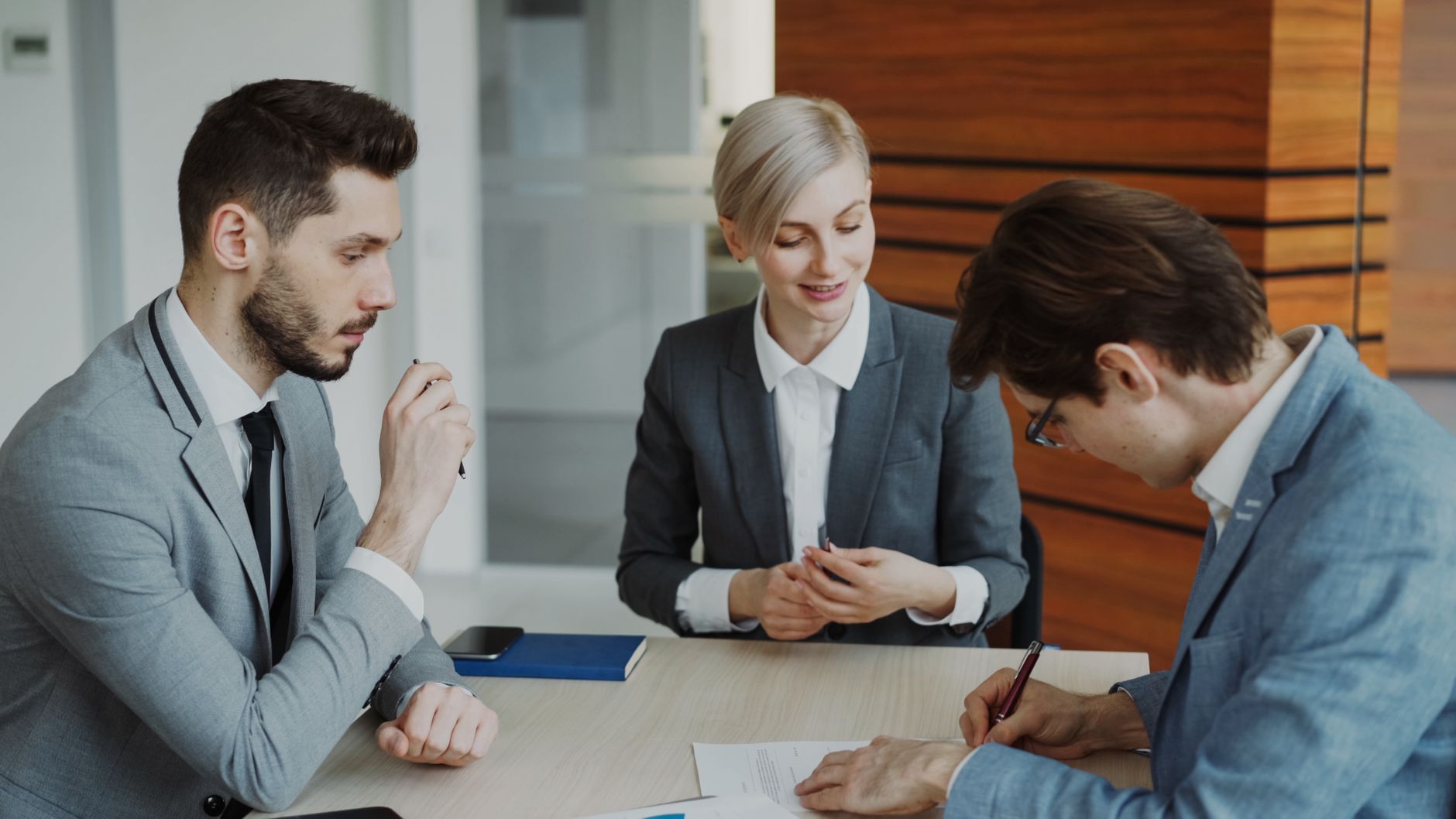 Profissionais do mercado imobiliário analisando contratos e dados em reunião corporativa