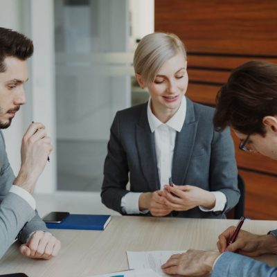 Profissionais do mercado imobiliário analisando contratos e dados em reunião corporativa