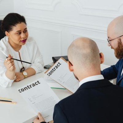 Profissional imobiliário atende cliente em ambiente corporativo, com foco em negociação e análise de imóveis.