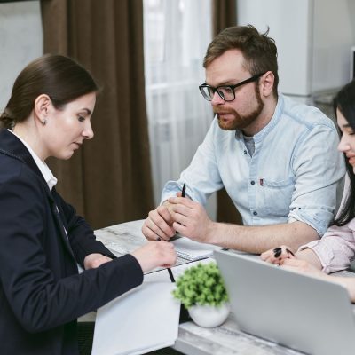 Profissional orientando clientes sobre financiamento para aquisição de imóvel residencial acessível