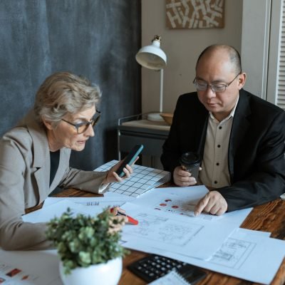 Reunião profissional para análise de documentos e mapas urbanos em ambiente corporativo